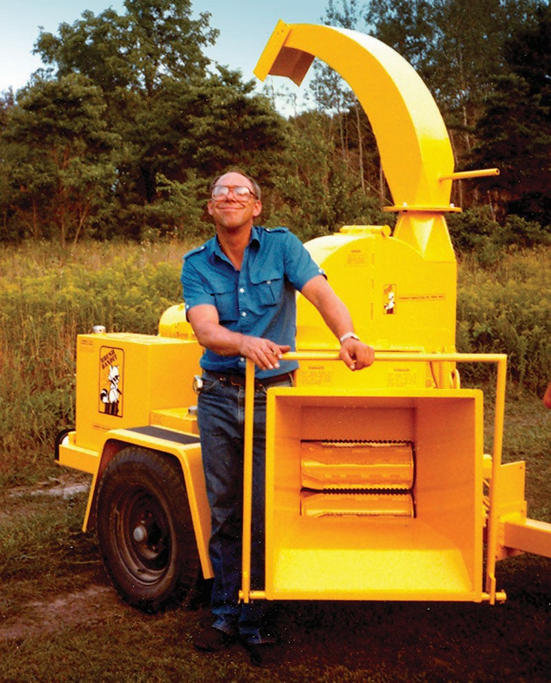 Mike Morey Sr. proudly stands next to the Brush Bandit, the original chipper that launched Bandit Industries. 