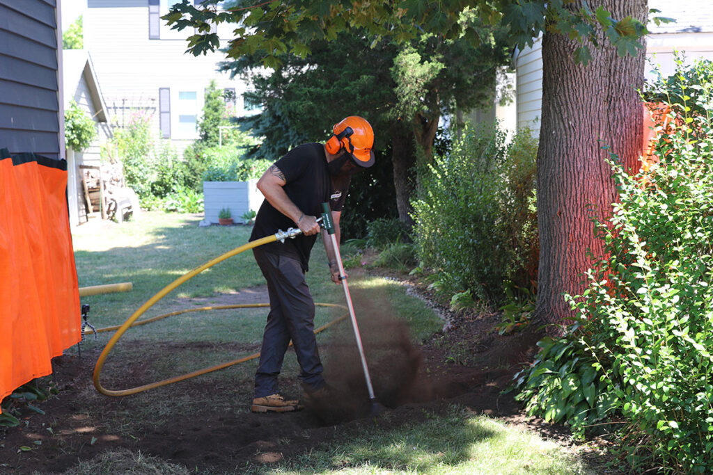 An arborist uses Arborjet’s Supersonic Air Knife pneumatic soil excavator to delicately work around tree roots. Source: Arborjet