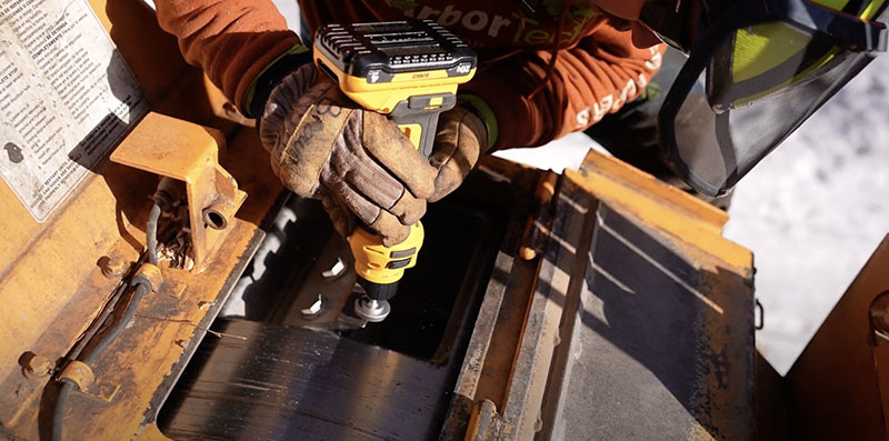 A maintenance worker using an ArborEdge sharpening system on a chipper blade.