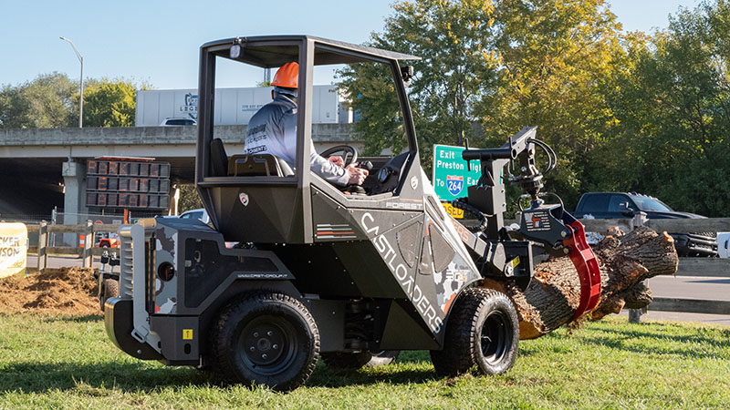 A tree worker operating a track loader with a grapple attachement.