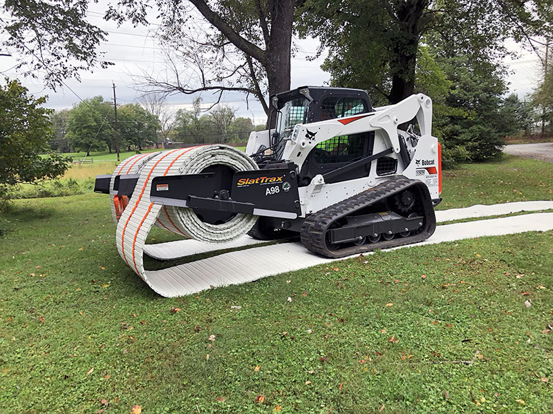 A skid steer deploying SlatTraxx protective mats.