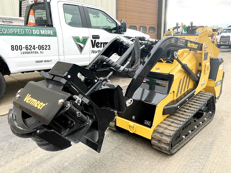 A Vermeer skid steer with a grapple attachment.