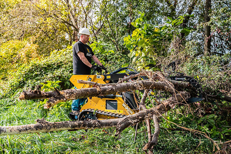 A tree worker uses a skid steer to move debris.