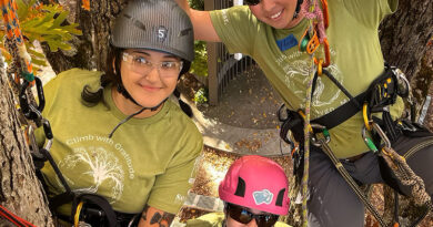 Attendees at a Women's Tree Climbing Workshop wearing climbing gear and PPE while in a tree.